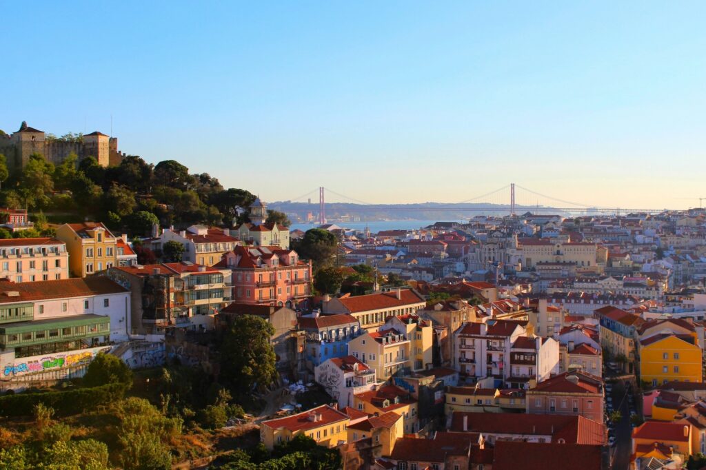 Lisbon rooftops and the 25 de Abril Bridge at sunset, host city of Web Summit and one of the biggest startup events in Europe